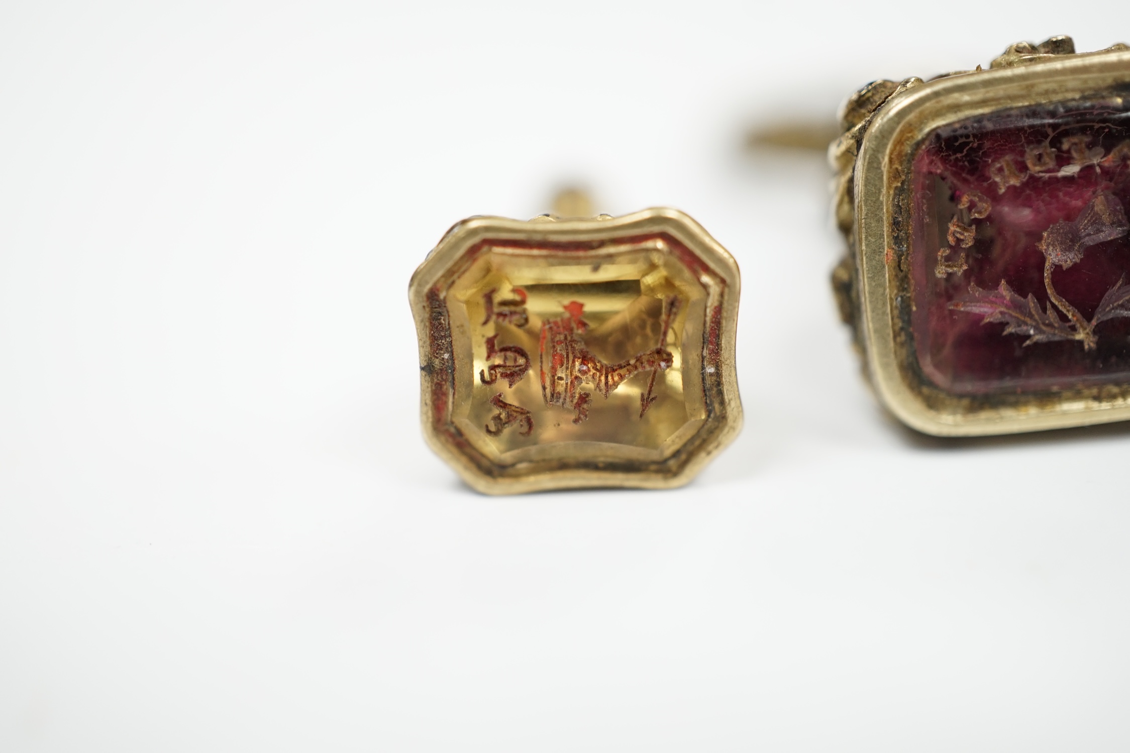 Two 19th century yellow metal overlaid and gem set fob seals, the largest with matrix carved with thistle and motto, 25mm.